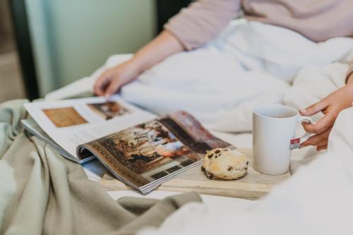 a person sitting in bed with a book and a cup of coffee at Summerstrand Escape Bella Mare in Gqeberha