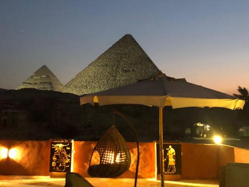 an umbrella in front of the pyramids at night at El Khalil Pyramids View Inn in Cairo