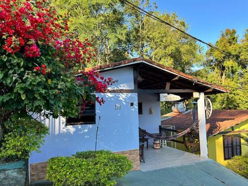 a small white house with red flowers at Pousada e Chalés Arco-Íris in Lima Duarte