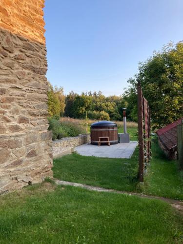 a hot tub in a yard next to a stone wall at Stodola 63 in Pacov