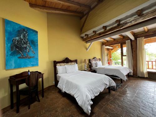 a bedroom with two beds and a painting on the wall at Hacienda Jimenita Wildlife Reserve in Puembo