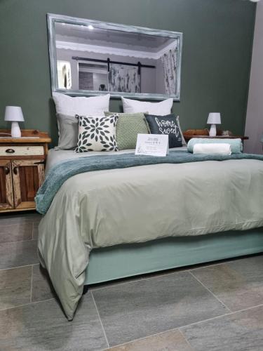 a bedroom with a large bed with pillows and a mirror at Grace B&B in Potchefstroom