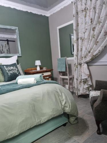 a green bedroom with a bed and a chair at Grace B&B in Potchefstroom
