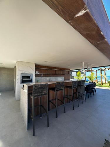 an open kitchen with a bar with stools at Mirante do Porto in Porto De Galinhas
