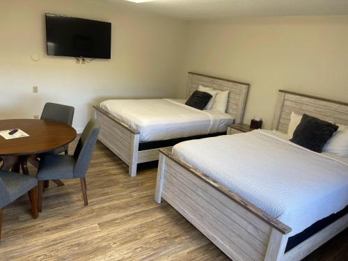 a hotel room with two beds and a table and a tv at The Patch Lodge in Warroad
