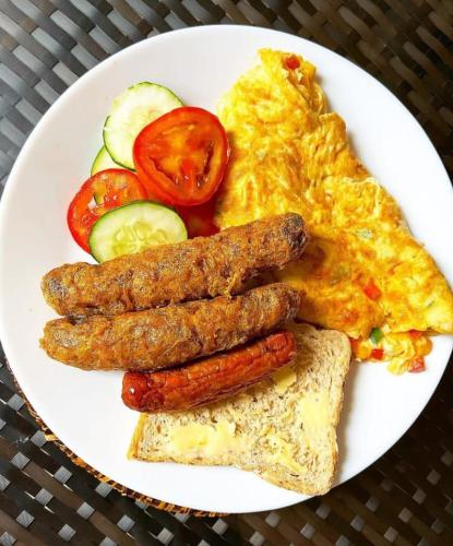 a plate of breakfast food with sausage eggs and tomatoes at Green Villa Apartments in Kigali