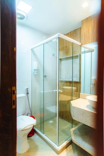 a bathroom with a glass shower and a toilet at Villa Peixe Na Telha in Porto De Galinhas