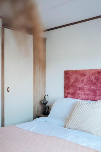 a bedroom with a white bed with a pink headboard at Foxglove Lodge in New Quay