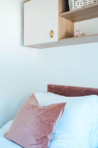 a bed with a pink pillow and a shelf at Foxglove Lodge in New Quay