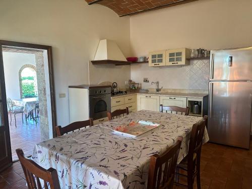 a kitchen with a table with chairs and a refrigerator at Agriturismo La Peschiera in Casole dʼElsa