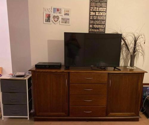 a television on top of a wooden dresser at Family home close to Melb Airport, free FAST WIFI! in Craigieburn
