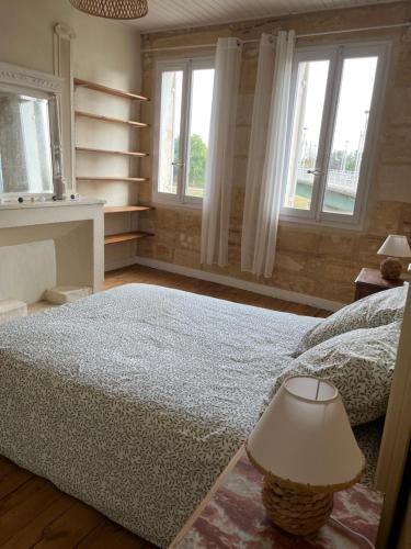 a bedroom with a bed with a lamp and two windows at Maison de ville in Port-Sainte-Foy-et-Ponchapt