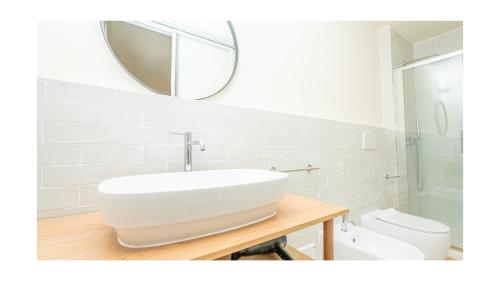 a white bathroom with a sink and a mirror at Green Guest House Alghero in Alghero