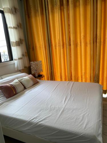 a bed in a bedroom with yellow curtains at Casa Almera in Totolan