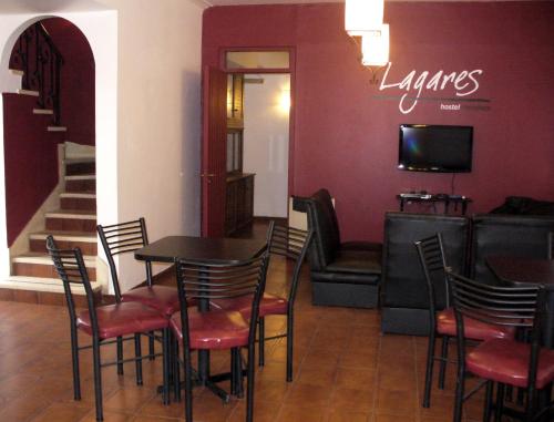 a dining room with a table and chairs and a television at Hostel Lagares in Mendoza