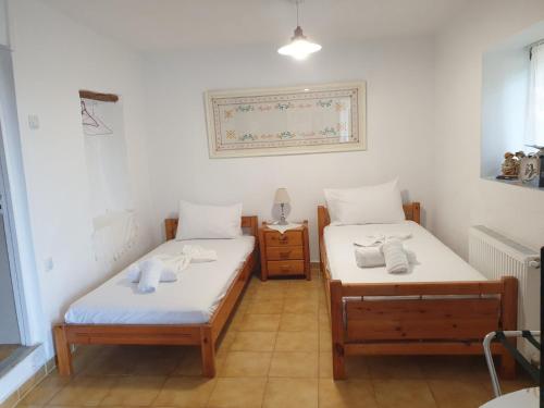 two twin beds in a room with white walls at Traditional House with breathtaking view, Makis in Sívros
