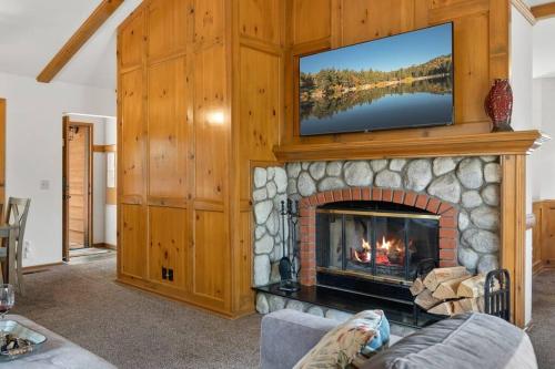 a living room with a fireplace with a tv above it at Cozy 3BR Dog-Friendly Cabin- Level 2 EV Chgr in Lake Arrowhead