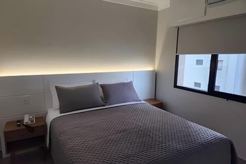a bedroom with a bed with two pillows and a window at Airfamily Congonhas in Sao Paulo