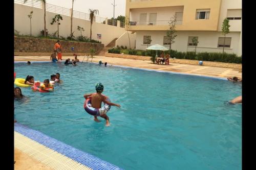 a group of people swimming in a swimming pool at Appartement à Cap de l'eau, vue piscine in Ras El Ma