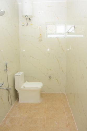 a white bathroom with a toilet and a window at Happy Nest Villa in Mahabalipuram