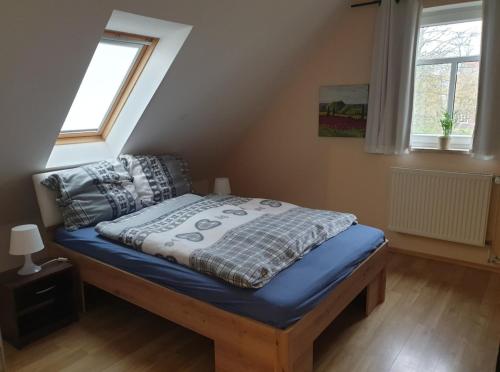 a bedroom with a bed with blue sheets and two windows at Fewo David und Marion oben, nahe der Nordsee und dem Weser Radweg in Golzwarderwurp