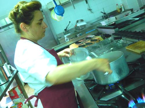 a woman in a kitchen preparing food in a pot at Tenuta Montelaura in Forino