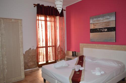 a bedroom with a white bed and a red wall at Butterfly Accommodation in Alghero