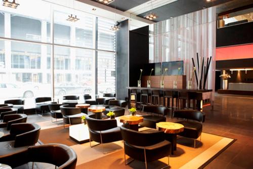 a restaurant with chairs and tables and a large window at Le Germain Hotel Maple Leaf Square in Toronto