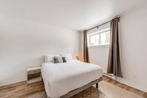 a white bedroom with a bed and a window at La Pionnière - 5 chambres - 13 personnes in Saint-Férréol-les-Neiges