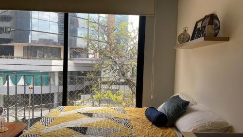 a bedroom with a bed and a large window at Corazón urbano, apartamento Guatemala zona 10 EON in Guatemala