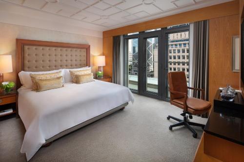a bedroom with a bed and a desk and a chair at Mandarin Oriental, Hong Kong in Hong Kong