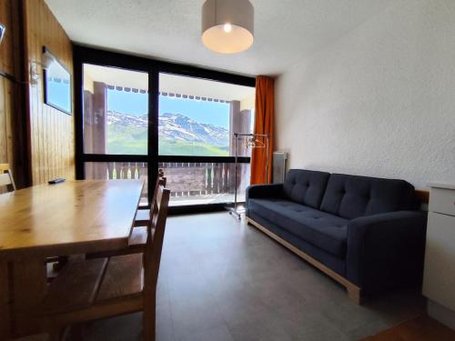 un salon avec un canapé bleu et une table dans l'établissement Résidence Lac Du Lou - VAL THORENS location: Appartement de 38 m2 au 7ème étage, skis aux pieds, balcon exposé sud MAE-9021, à Val Thorens