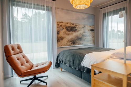 a bedroom with a bed and a chair and a window at Liiv Coast Cottages in Ģipka