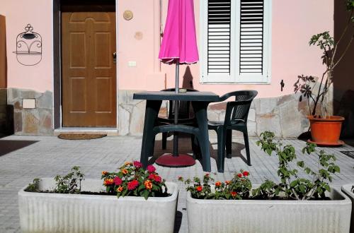 a table and chair in front of a house with flowers at Butterfly Accommodation in Alghero