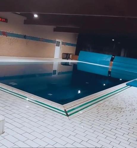 a swimming pool with a blue bench in a room at Heerlijk Huys, Vakantievilla met privé tuin in Ewijk