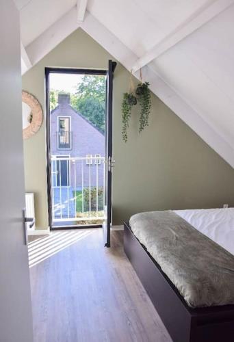 an attic room with a bed and a large window at Heerlijk Huys, Vakantievilla met privé tuin in Ewijk