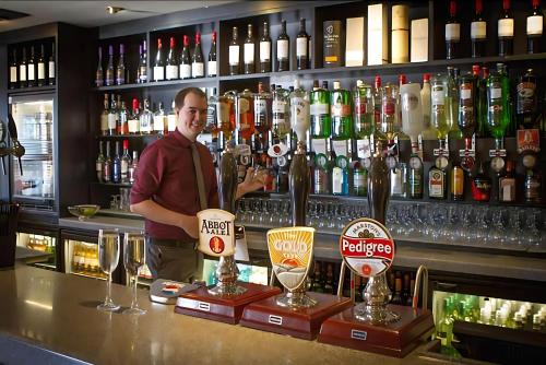 a man is standing behind a bar withbeer glasses at Staindrop Hotel in Sheffield