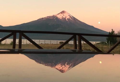 a mountain in the background with a reflection in the water at Espectacular casa orilla de lago in Puerto Varas