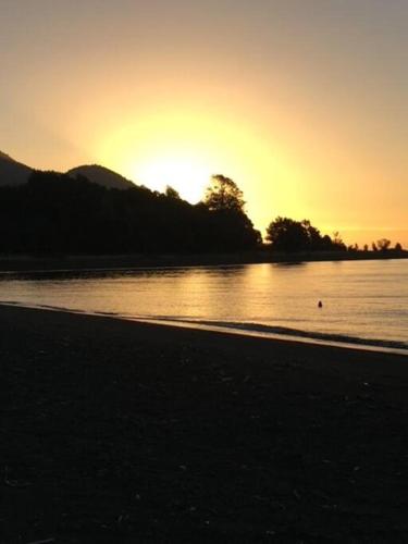 a sunset on a beach with a body of water at Espectacular casa orilla de lago in Puerto Varas