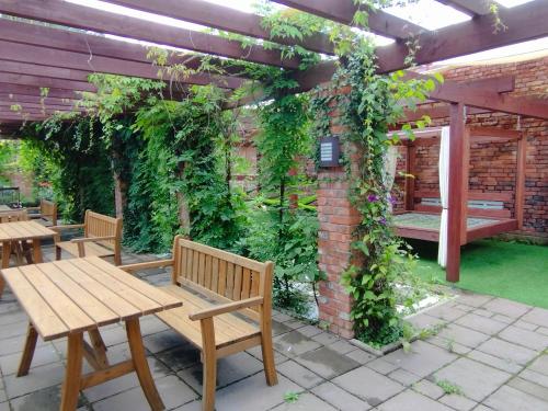 a patio with benches and a brick wall with ivy at Noclegi Szymrych in Chełmsko Śląskie