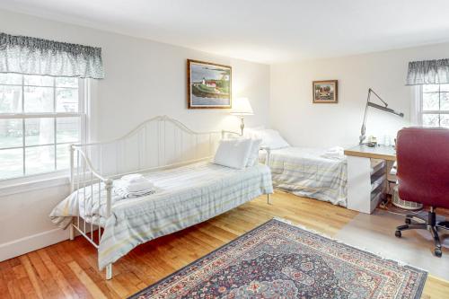 a bedroom with two beds and a desk and a chair at Falmouth Beachtown Getaway in Falmouth