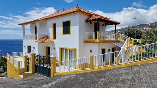 a yellow and white house with the ocean behind it at Sol e Mar by the airport in Santa Cruz
