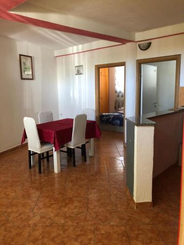 a dining room with a red table and white chairs at Apartmani CESARICA in Karlobag