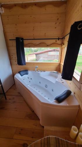 Lisle-sur-TarnにあるTiny House Petite Balnéo Cheminée exterieureの窓付きの木製の部屋(大きな白いバスタブ付)
