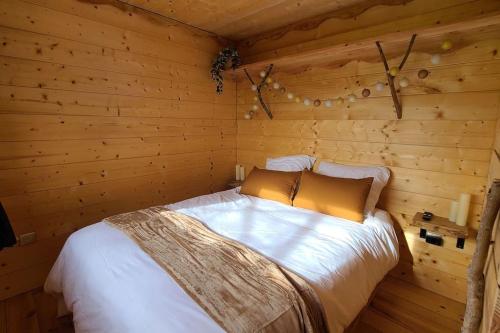 une chambre avec un lit dans une cabane en rondins dans l'établissement Tiny House Petite Balnéo Cheminée exterieure, à Lisle-sur-Tarn