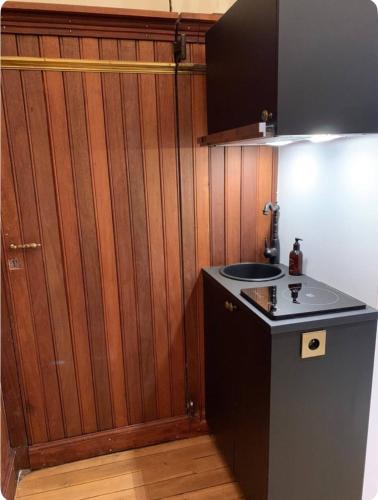 - une cuisine avec un évier et un mur en bois dans l'établissement Studio Paris 7e Tour Eiffel, à Paris