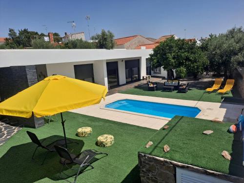 a yellow umbrella on a yard with a swimming pool at Mourão Retreat in Mourão