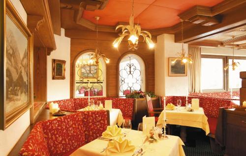 a restaurant with tables and chairs and a chandelier at Sporthotel Schönruh in Ehrwald
