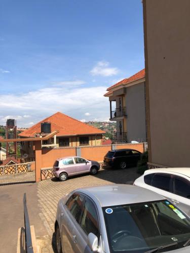 two cars parked in a parking lot in front of a house at Casa Homes Apt2 with unlimited Wi-Fi in Kampala