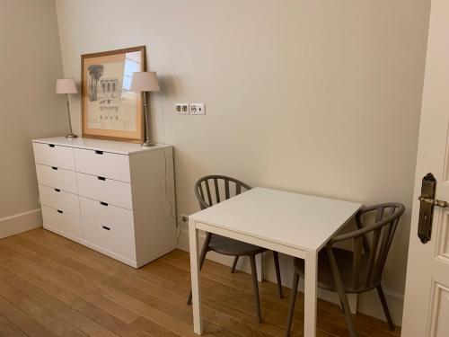 Cette chambre comprend une table et des chaises blanches ainsi qu'une commode. dans l'établissement Appartement Tour Eiffel Invalides 7e G, à Paris